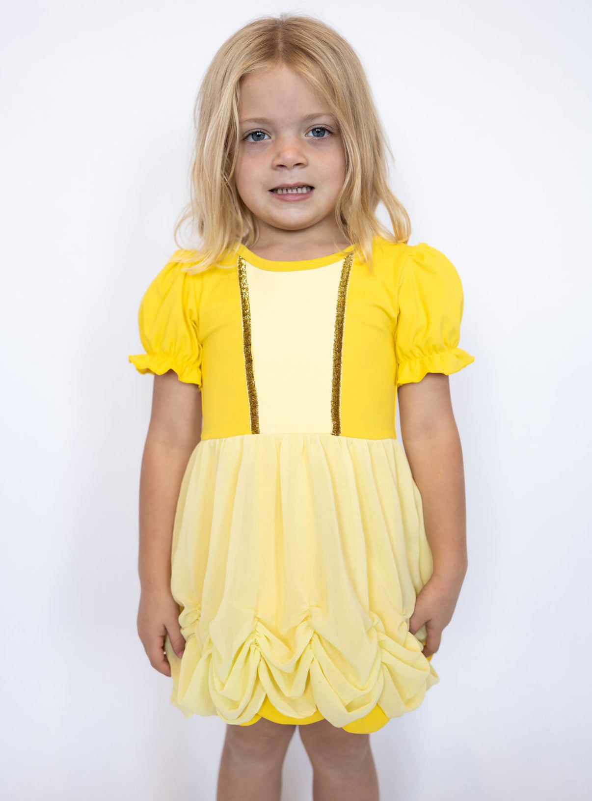 Soft puff sleeves with ruffle trim for a classic princess look
Golden bodice with sparkling trim accents
Gathered, ruched skirt for an elegant ballgown feel
Sweet bow-back cutout detail for extra charm
Built-in matching shorts for all-day comfort and play
Lightweight, stretchy fabric that moves with your little one