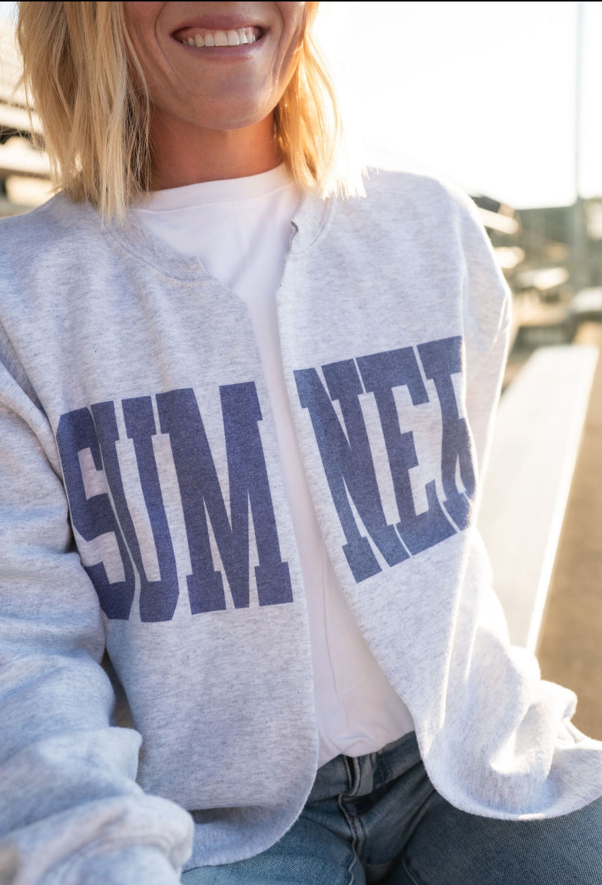 Absolutely! Here's the updated Shopify description with the correct color:
---
**Sumner Sweatshirt Cardigan – Women’s**
Show your local pride in comfort and style with our Sumner Sweatshirt Cardigan! This cozy layering piece features a classic varsity-style “SUMNER” graphic across the front in **bold purple lettering**, perfect for game days, school events, or everyday errands around town.
🟣 **Details:**
* Heather gray with **purple block lettering**
* Open-front cardigan style (no buttons or zippers)
