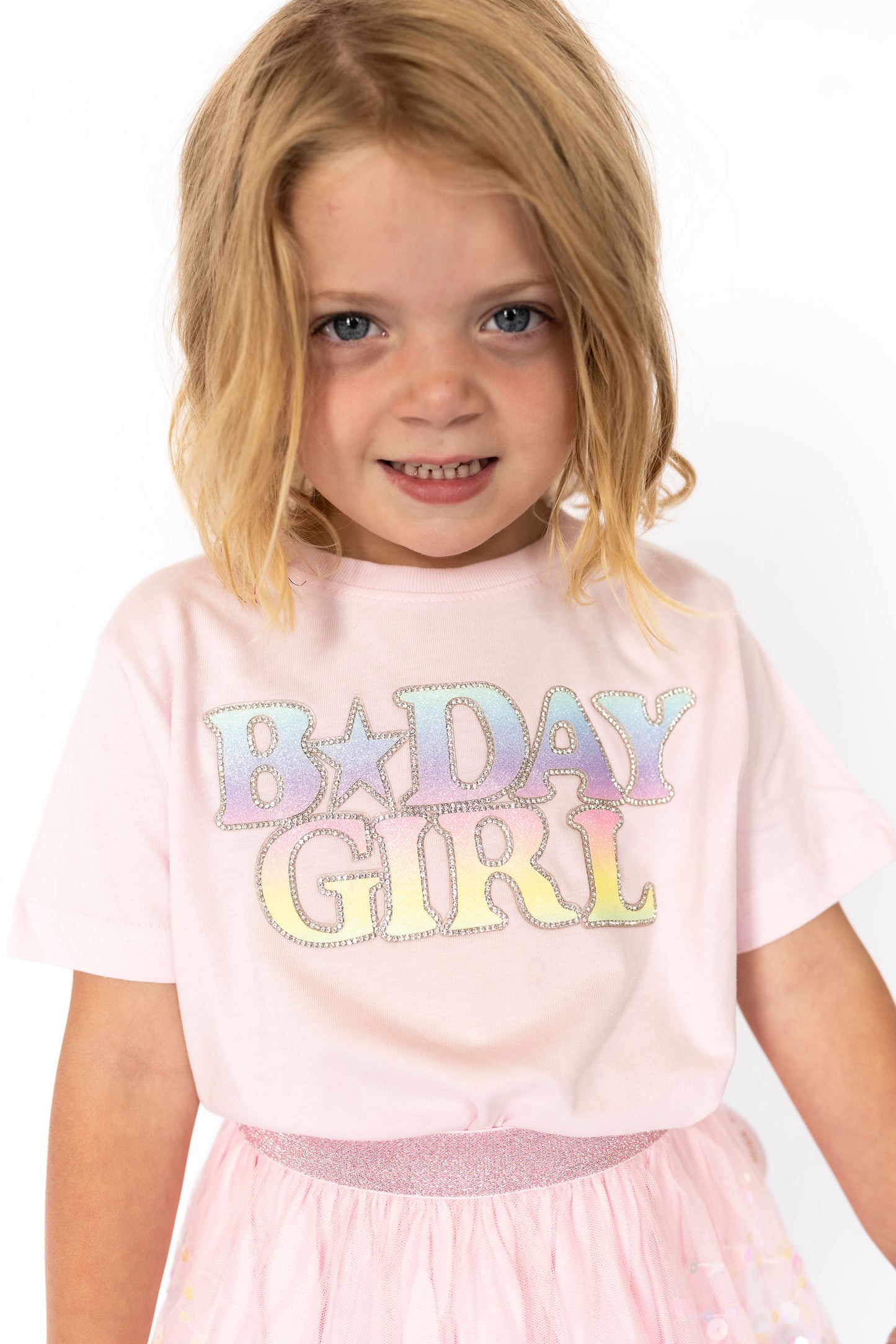Let the birthday girl shine bright in this adorable pastel party tee! Featuring a magical ombré rainbow design outlined in rhinestones, this soft pink shirt is made for twirling, giggling, and blowing out candles in style.