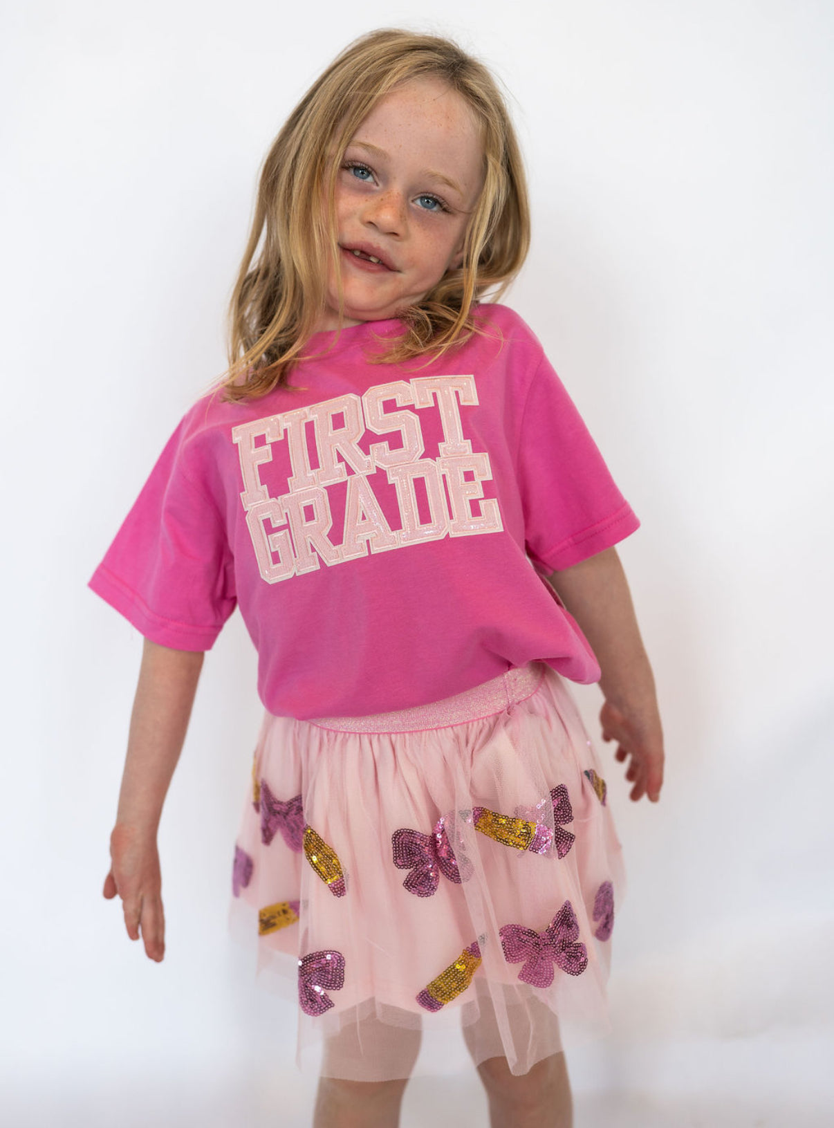 Details:
Soft, breathable cotton blend for all-day comfort
Pink sequin “FIRST GRADE” graphic in bold varsity lettering
Unisex fit pairs easily with skirts, jeans, or leggings
Perfect for first-day-of-school photos and milestone celebrations
Available in youth sizes