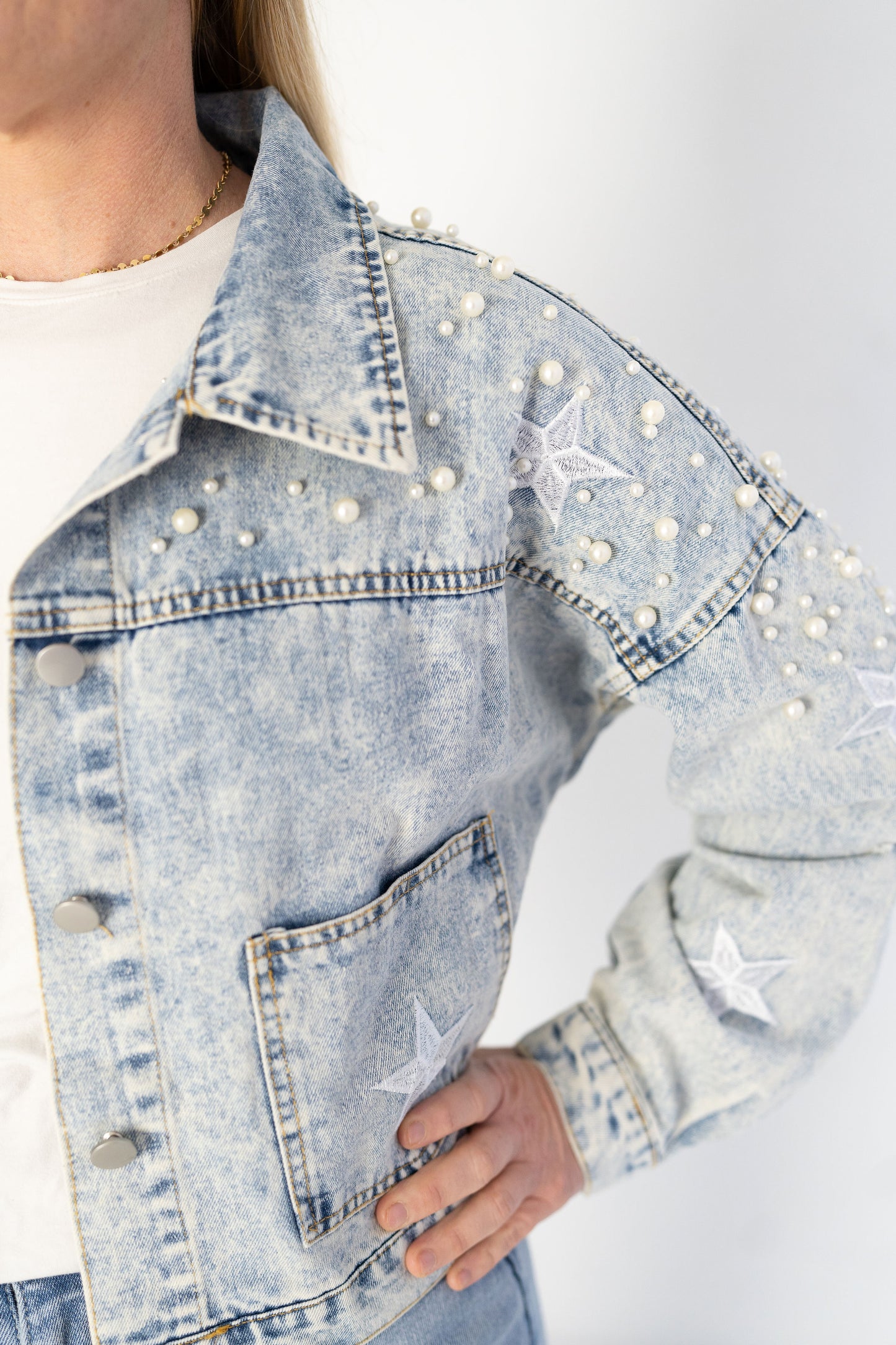 Women's oversized denim wash jean jacket with pearl details, embodied stars and pockets.