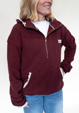 Person wearing a maroon half zip hoodie with lace detail