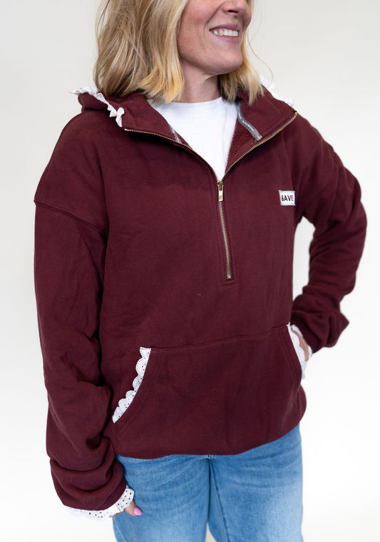 Person wearing a maroon half zip hoodie with lace detail