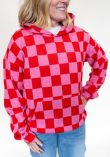 Person wearing a red and pink checkered hoodie against a white background. 