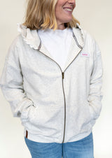 Person wearing a light gray hoodie with a brand logo and lace detail
