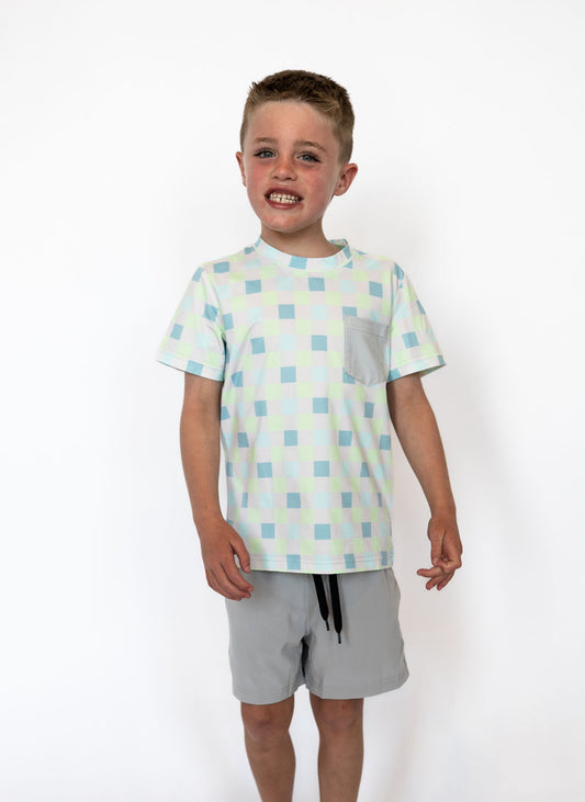Pastel checkered pattern in shades of mint, blue, and white

Solid light gray chest pocket for added style

Soft, lightweight, and breathable fabric for all-day comfort

Crew neckline and short sleeves for easy movement

Pairs perfectly with our Boys Double Layered Shorts to complete the look

Available in boys sizes 2T–9/10
