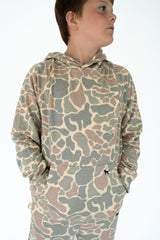Boy wearing camouflage hoodie and matching pants on a white background