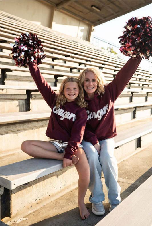  Details:

Rich maroon pullover with soft fleece interior
Oversized white “Cougars” chenille patch
Front kangaroo pocket for all the essentials
Ribbed cuffs and waistband for a secure fit
Women’s sizes S–XL
Unisex fit for a relaxed, everyday feel
