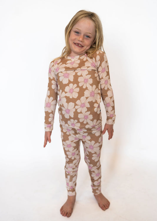 Made from buttery-soft bamboo fabric that’s breathable and temperature regulating
Ribbed texture for extra stretch and comfort
Playful tan base with ivory daisies and pink centers for a cheerful look
Two-piece set with a long-sleeve top & matching pants
Hypoallergenic and eco-friendly fabric that moves with them
