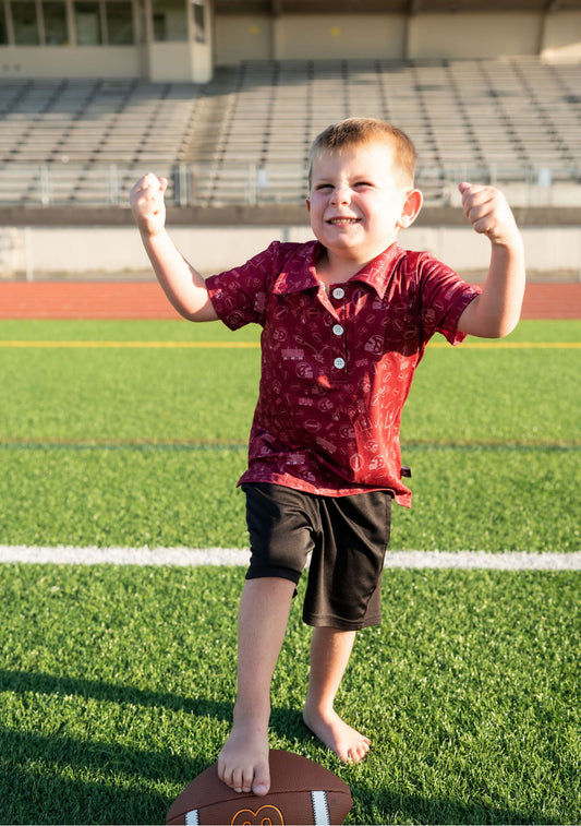 🏈 Details:

Maroon polo with tonal football doodle print (helmets, fields, foam fingers & more!)
Lightweight, breathable performance fabric
Classic collar with 3-button placket
Unisex fit – great for toddlers and kids alike
Sizes 2T–7/8