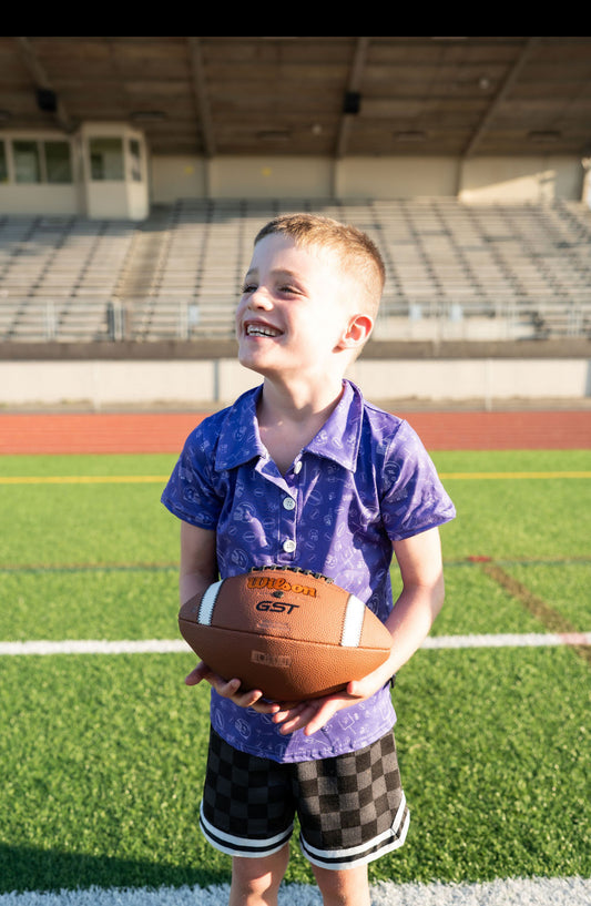 🏈 Details:

Vibrant purple fabric with tonal football-themed doodle print
Button-up collar for that dressed-up-but-ready-to-rumble vibe
Soft, lightweight performance-style material—great for running, cheering, or touchdown dancing
Unisex fit, available in sizes 2T through 7/8
🔥 Perfect for school spirit days, Saturday tailgates, or backyard football showdowns. This polo is game day goals.
