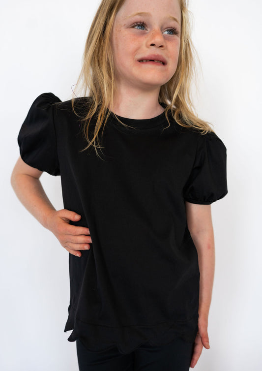 Classic black for effortless pairing

Scalloped hem for a subtle, girly flair

Short puff sleeves with elastic cuffs

Soft, stretchy fabric for all-day comfort

Works great with leggings, jeans, or skirts

Available in toddler &amp; youth sizes 2T–9/10