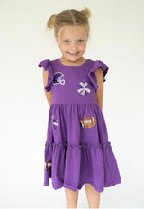 A young girl  wearing a purple tiered dress with football-themed sequins patches.