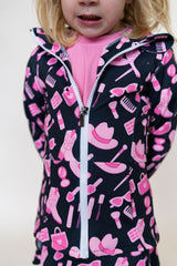 Child wearing a dark jacket with pink and white patterns on a plain background