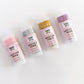 Five lip balm tubes with different colored tops on a white background Pink, Purple, Silver and Gold glitter sticks for hair and body