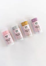 Five lip balm tubes with different colored tops on a white background Pink, Purple, Silver and Gold glitter sticks for hair and body