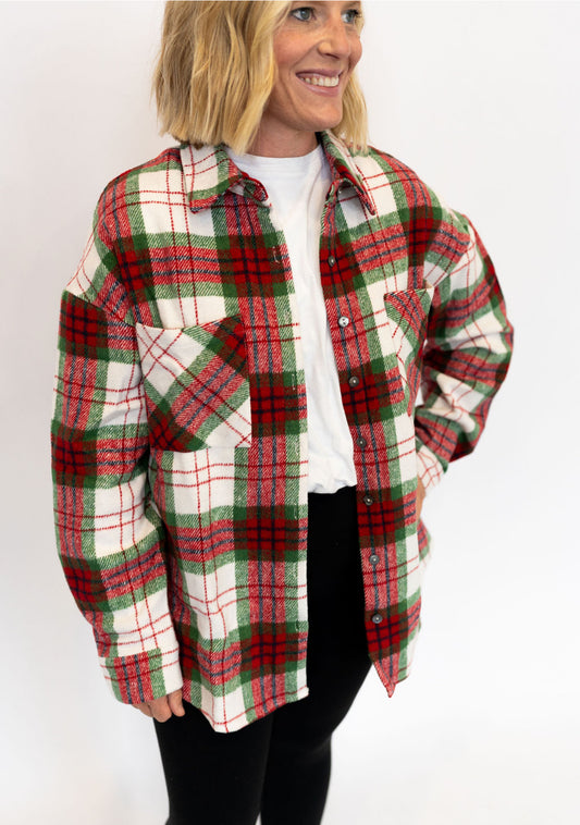 Person wearing a red and green plaid shirt over a white top on a white background