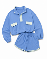 A two-piece kids' athletic set in light blue, featuring a long-sleeve quarter-placket pullover with light blue contrast trim and matching drawstring shorts with white contrast trim.