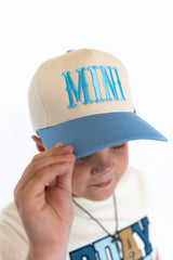 Embroidered “MINI” in bright blue
Cream crown + blue bill = instant cool,,Adjustable snapback
Comfy, lightweight, and kid-approved