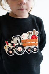 Child wearing a black sweatshirt with a baseball-themed truck design chenille patch