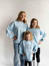 Mom and kids wearing matching Lulu Mac light blue mono crewnecks. 