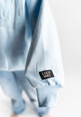 Lulu Mac sleeve logo detail on light blue crewneck sweatshirt. 