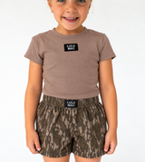 Lulu Mac Youth Baby Doll Tee in dark taupe with short sleeves, a fitted silhouette, and a black Lulu Mac logo patch at the chest.