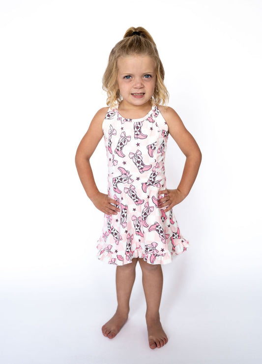 This dress is where cowgirl dreams meet twirly queen energy! Featuring a soft pink gingham backdrop, cow-print boots, darling bows, and sweet little stars — it’s the ultimate outfit for your mini wildflower