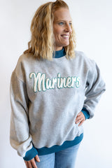 Women’s Mariners sweatshirt heather gray with teal embroidered script logo, casual outfit with jeans and layered teal top