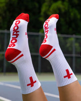 White socks with red accents and 'Pathos' branding on a blurred outdoor background