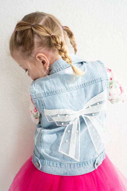 toddler and youth sized denim vest with lace and pearl bow attached on the back