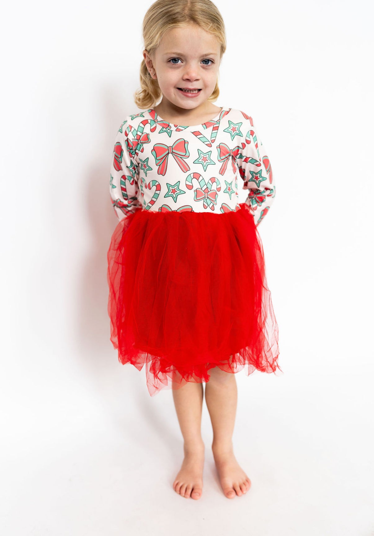 Young girl wearing a festive dress with a red skirt and patterned top on a white background