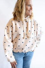 Women’s cream polka dot hoodie with navy dots, drawstring hood and front pocket, casual cozy sweatshirt styled with jeans
