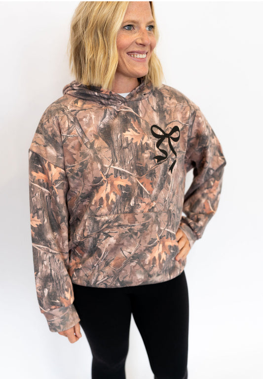 Allover brown and green camo print
Signature black bow graphic on front chest and larger on back
Soft, midweight fabric for year-round wear
Front kangaroo pocket
Ribbed cuffs and hem for a snug fit
Simply Southern logo detailing
Unisex fit — perfect for that “borrowed from the boys, but make it cute” vibe
Available in sizes XS–XXL
