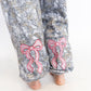 Gray camouflage pants with pink bow designs on a white background