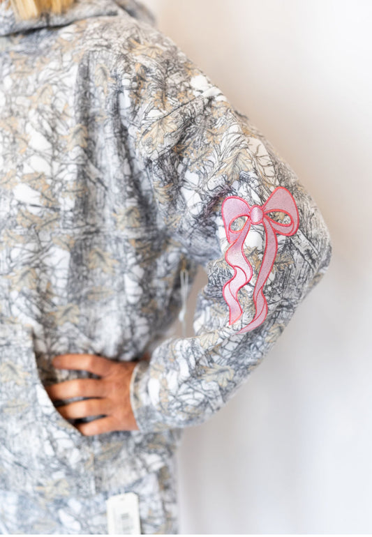 Allover grey and tan camo print
Embroidered pink bow accents on sleeves 🎀
Soft fleece interior for all-day comfort
Front kangaroo pocket
Relaxed, oversized fit
Hooded with drawstring
Available in sizes XS–XXL