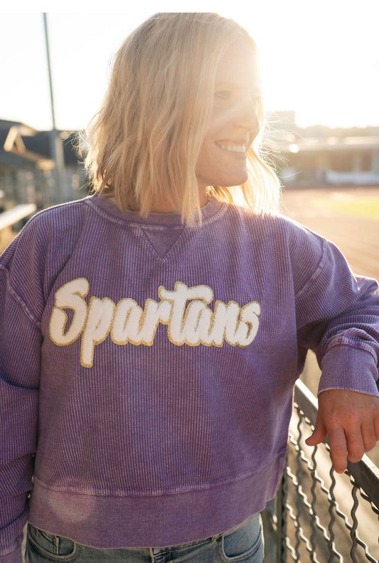 Details:

Mineral-washed purple corded fabric

White chenille "Spartans" script with gold glitter outline

Relaxed, comfy oversized fit

Ribbed neckline, cuffs, and hem for a polished look

Available in sizes S-XL

