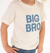 A child wearing a Sweet Wink light heather cream t-shirt with 'BIG BRO' embroidered in blue block letters on the front, paired with blue jeans against a white background.