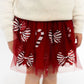 Red tulle skirt with candy cane patterns worn by a person, on a plain background