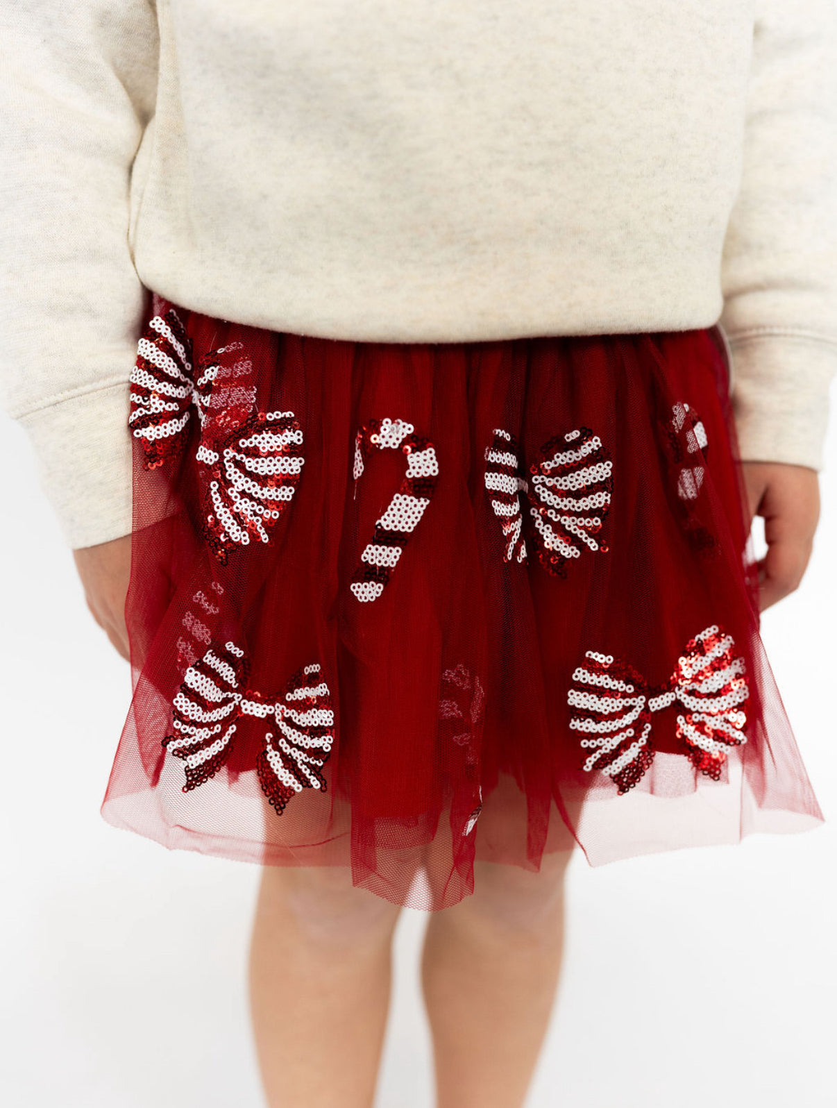 Red tulle skirt with candy cane patterns worn by a person, on a plain background