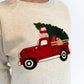 Beige sweater with a red truck and Christmas tree design on a white background