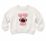 Toddler girls heather oatmeal Game Day sweatshirt with pink chenille and sequin lettering, football with pink bow graphic, and long sleeves on a clean white background.
