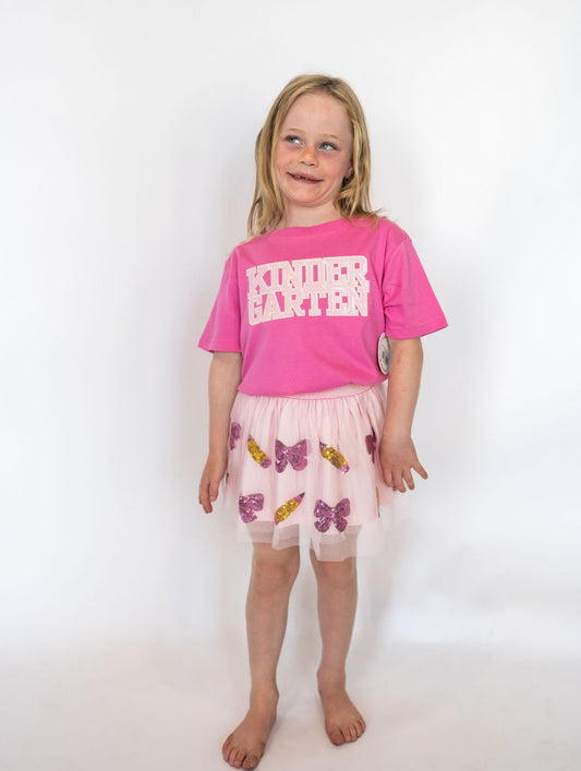 Send your little scholar off in style with the Sweet Wink “Kindergarten” tee! This bright pink shirt is sprinkled with sparkle thanks to its sequin-accented block lettering—perfect for making that first day photo extra special.

Details:

Soft, breathable cotton blend for all-day comfort
Pink sequin “KINDERGARTEN” graphic in bold varsity lettering
Unisex fit for easy styling with skirts, jeans, or leggings
Perfect for first-day-of-school outfits and milestone photos
Available in youth sizes
