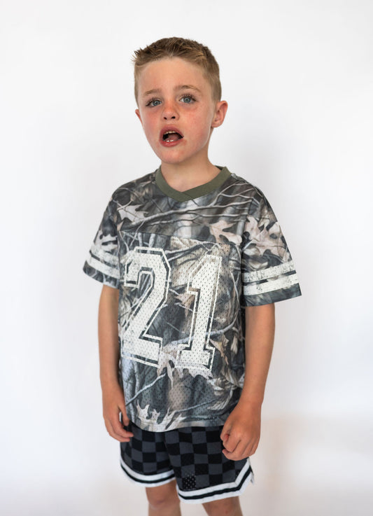 Details:

All-over camo print with white “21” graphic on front & back
Soft, breathable mesh fabric for comfort
Short sleeves with sporty stripe accents
Ribbed V-neckline for a classic jersey look
Available in toddler sizes 2T–6T