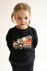 Child wearing a black sweatshirt with a baseball themed tractor chenille patch  on a plain background