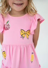 Close up picture of girl wearing pink dress with apple, and pencil sequins decals 