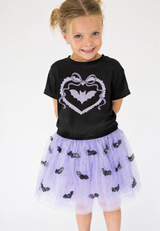 A young girl wearing Black toddler T-shirt featuring a cream and lavender heart with a sparkling rhinestone bat patch, perfect for Halloween and fall outfits.