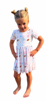 Girls pastel pink and blue football gameday twirl dress with footballs, cheer graphics, and “Touchdown” details, modeled on a clean white studio background.