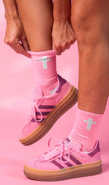 Pink Christian crew socks with white cross worn with pink Adidas Gazelle sneakers lifestyle photo