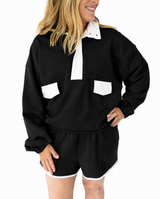 Black and white colorblock pullover sweatshirt featuring a white snap collar, white chest pocket accents, long sleeves, and a relaxed fit, paired with coordinating black shorts with white trim.
